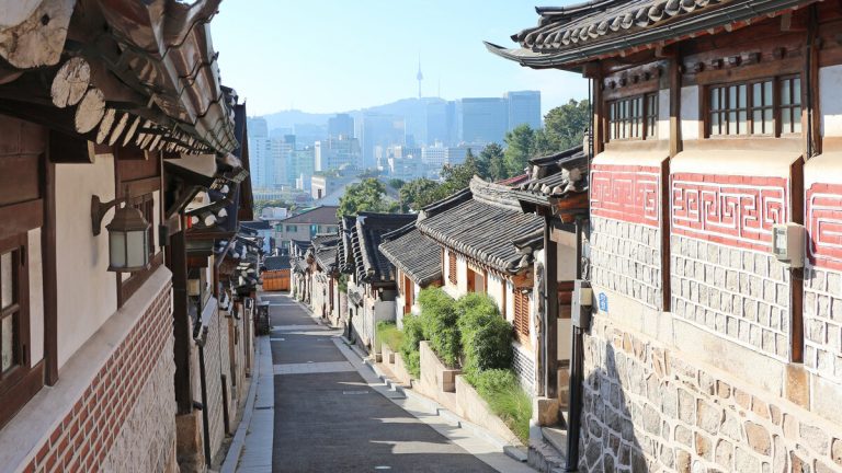 서울 북촌한옥마을의 기와지붕 골목과 멀리 보이는 도심 전경