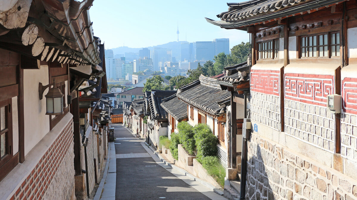서울 북촌한옥마을의 기와지붕 골목과 멀리 보이는 도심 전경